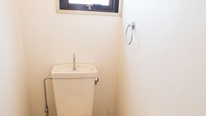 Un baño pequeño con inodoro, ventana y secador de manos.