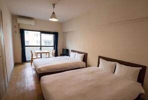 A hotel room with two beds, a desk, a chair, and a window with curtains. - Hotel Chaika in Fukuoka (Fukuoka)