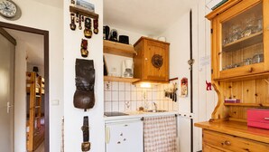 Een kleine keuken met houten kastjes, een koelkast en een wastafel.