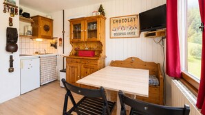 Een knus interieur met houten kastjes, een eettafel en stoelen.