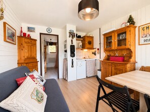 A compact living space with a kitchenette, a dining area, and a sofa with decorative pillows.