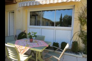 An outdoor patio with a table and chairs, a potted plant, and a window with a view of the sky and trees. - *** Villa ISOLINA *** (Vaison-la-Romaine)