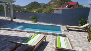 Relax by the serene pool surrounded by lush greenery and comfortable lounge chairs.