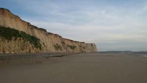 A beach with a cliff and a clear sky.