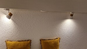 A bed with two pillows, a small round table, and a textured wall.