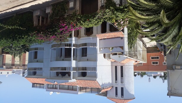 Un edificio de varios pisos con balcones y techo de tejas.