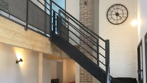 Un interior moderno con una escalera, comedor y un reloj en la pared.