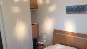 A bedroom with a bed, a nightstand, a lamp, and a wardrobe. - F2 on Bordagain Hill. Ciboure (Ciboure)