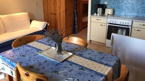 A cozy kitchen with a blue tiled backsplash, wooden cabinets, and a dining table with a floral tablecloth. - Spacious studio for 4 with balcony in Saint-Michel-de-Chaillol (Saint-Michel-de-Chaillol)