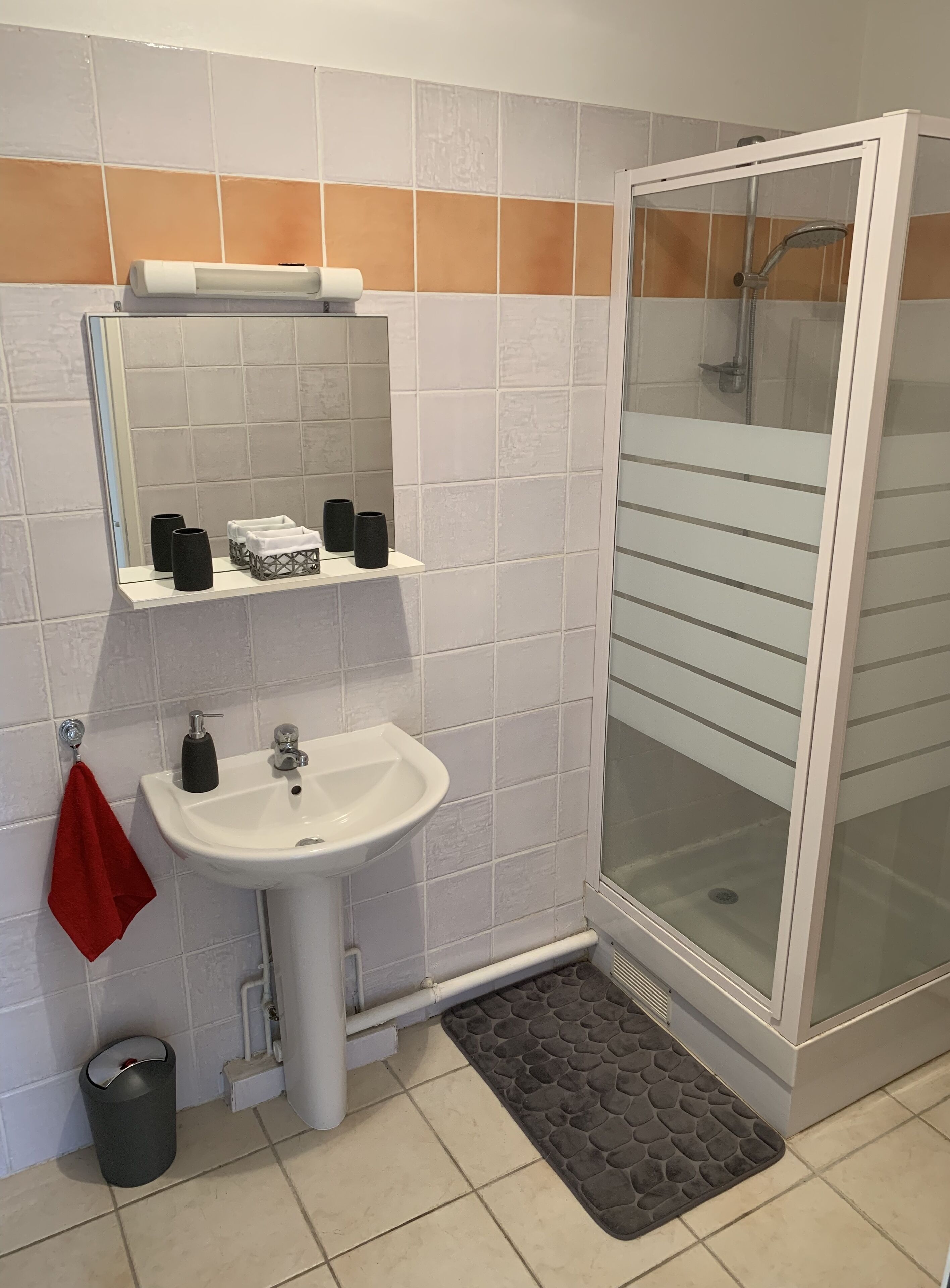 Un baño con lavamanos blanco, espejo y cabina de ducha de vidrio.