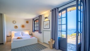 Een moderne slaapkamer met een groot bed, uitzicht op zee en een bijzondere cactussculptuur.