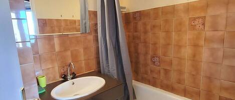 A bathroom with a white sink, a mirror, and a bathtub.