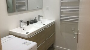 A modern bathroom with a white sink, a mirror, and a towel rack.