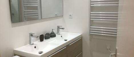 A modern bathroom with a white sink, a mirror, and a towel rack.