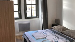 A bedroom with a bed, a wardrobe, a window with curtains, and a radiator.
