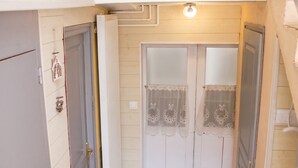 Un pasillo estrecho con un radiador blanco, una puerta con un panel de vidrio decorativo y una escalera a la derecha.
