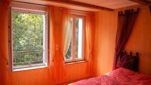 Un dormitorio con un ventanal grande, una cama y cortinas.