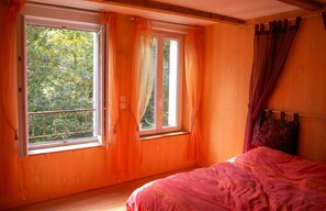 Un dormitorio con un ventanal grande, una cama y cortinas.