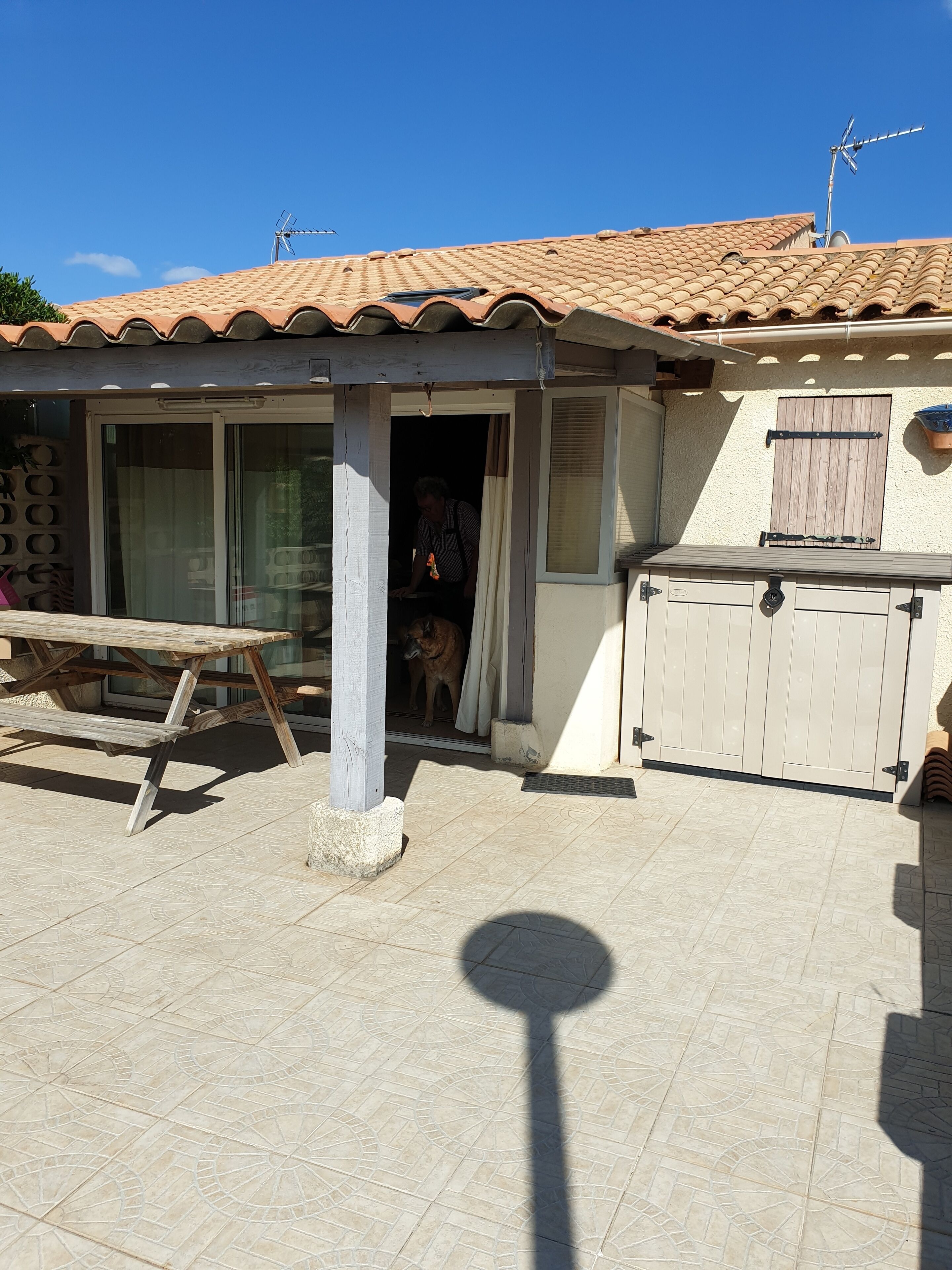Una casa con techo de tejas, puerta de madera y patio con mesa y sillas.