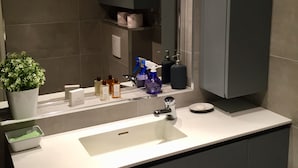 Uma casa de banho moderna com uma pia branca, armários escuros e uma planta em vaso.
