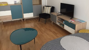 Uma sala de estar moderna com televisão, sofá, mesa de vidro e aparador.