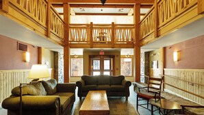 A lobby with a wooden balcony, a sofa, a table, and chairs.