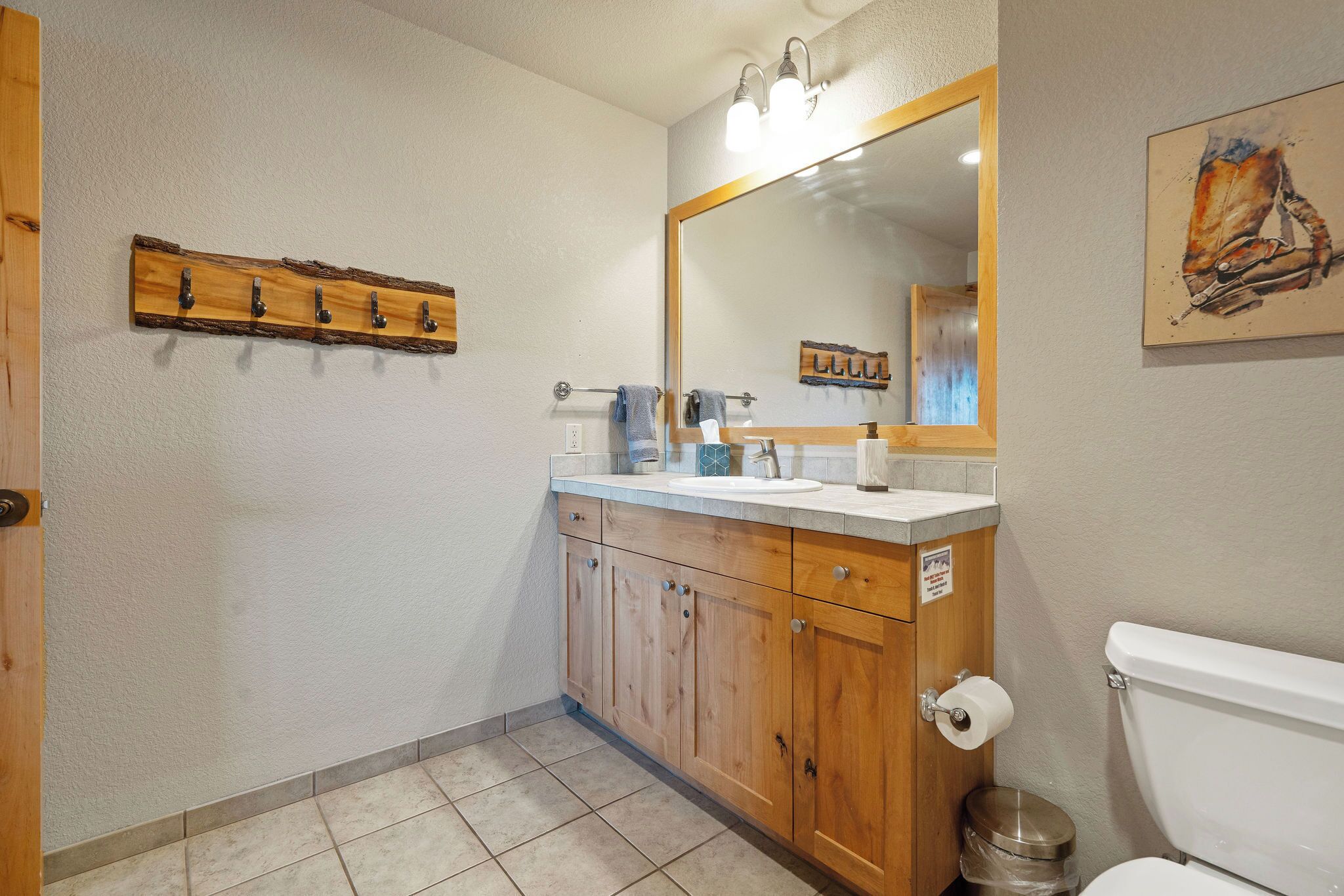 A bathroom with a wooden vanity, a sink, a mirror, and a toilet.