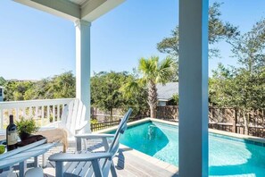 A covered outdoor area with a pool, white deck chairs, and a wooden fence. - Heated Private Pool*, Walk to the Beach! Golf Cart & 6 Bikes! - Blue Dune 30A in Blue Mountain Beach (Santa Rosa Beach)