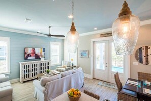 A living room with a television, a ceiling fan, and a dining area with a table and chairs. - Heated Private Pool*, Walk to the Beach! Golf Cart & 6 Bikes! - Blue Dune 30A in Blue Mountain Beach (Santa Rosa Beach)