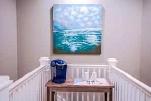 A staircase with a coffee maker on a table, a painting of a seascape, and white railings. - Heated Private Pool*, Walk to the Beach! Golf Cart & 6 Bikes! - Blue Dune 30A in Blue Mountain Beach (Santa Rosa Beach)