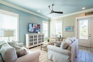 A spacious living room with a ceiling fan, a television, and a light blue wall. - Heated Private Pool*, Walk to the Beach! Golf Cart & 6 Bikes! - Blue Dune 30A in Blue Mountain Beach (Santa Rosa Beach)