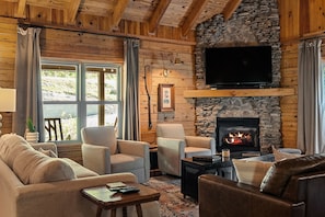Una sala de estar acogedora con chimenea de piedra, asientos cómodos y un televisor de pantalla plana sobre la chimenea.