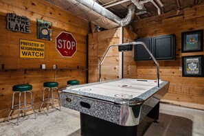 Een houten interieur met een jeu de boules baan, krukken, een stopbord en diverse ingelijste decoraties aan de muur.