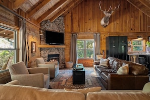 A rustic cabin interior with a stone fireplace, leather sofas, a mounted deer head, and a stone wall. - Boat Days Begin Here, Walk to  Hurricane Marina (silver point)