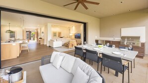 Un vaste espace de vie comprenant un coin repas avec table, un canapé et une cuisine équipée d’un barbecue.