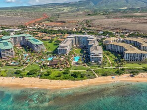 A resort with multiple buildings, a central pool, and a beach.