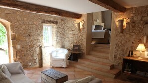A stone-walled room with a white armchair, a wooden coffee table, and a sofa. - Elegant Provence Retreat with Infinity Pool – Near Aix-en-Provence (Rians)