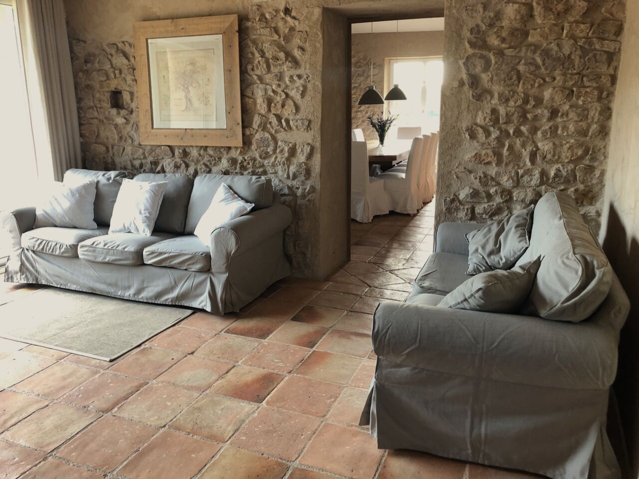 A living room with two grey sofas, a stone wall, and a framed picture.