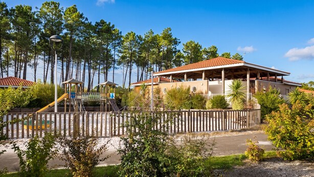 A beachside resort with a wooden building, a playground, and a fenced area. - Homerez - House in Parentis-en-Born (Parentis-en-Born)