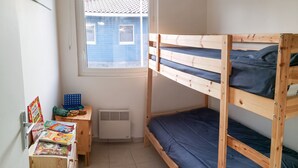A bunk bed room with a window, a small desk with books, and a heater. - Homerez - House in Parentis-en-Born (Parentis-en-Born)