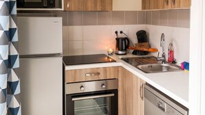 A compact kitchen with a microwave, oven, dishwasher, and wooden cabinets. - Homerez - House in Parentis-en-Born (Parentis-en-Born)