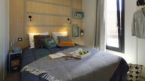 A bedroom with a bed, bedside tables, a window with curtains, and a wall-mounted shelf with decorative items. - St Maurice - Plein Air Chalet C1 (Dieulefit)