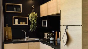 A modern kitchen with wooden cabinets, a black countertop, a stainless steel sink, a hanging plant, and a microwave. - St Maurice - Plein Air Chalet C1 (Dieulefit)