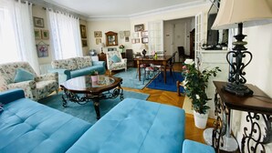 A living room with a blue sofa, a coffee table, and a dining area with a table and chairs.