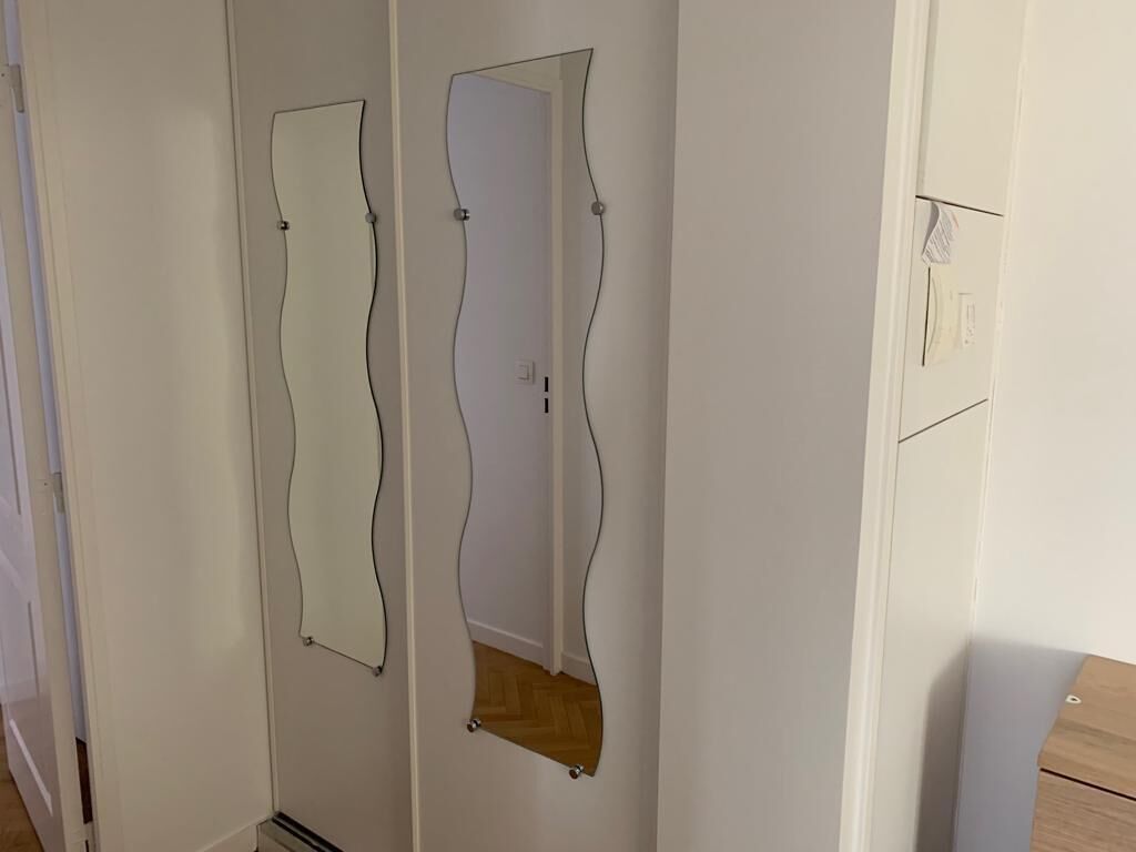 Ein Flur mit zwei Türen, jede mit einem besonderen, wellenförmigen Spiegeldesign.