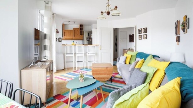 A modern living room with a sofa, colorful rug, and a small table.