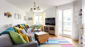 A modern living room with a sofa, TV, and a colorful rug.