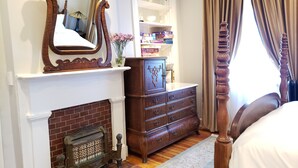 A bedroom with a fireplace, a wooden dresser, a large mirror, and a bed. - Downtown, 2 Parking spaces, Historic Beauty (Richmond)