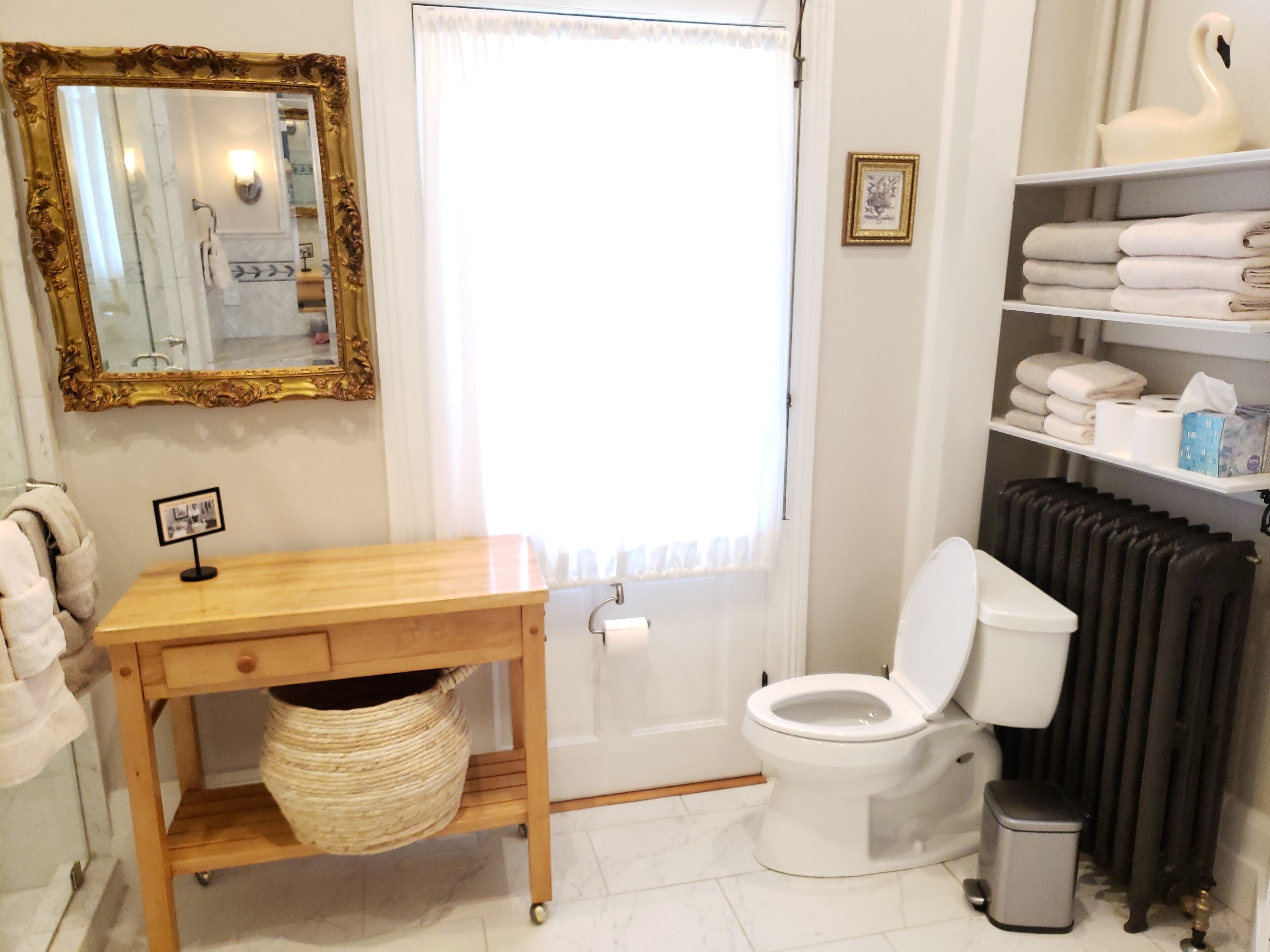 Un baño con inodoro, lavabo con espejo, toallero y radiador.