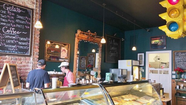A bakery with a glass display case filled with pastries and a chalkboard menu listing items like gelato and coffee. - Downtown, 2 Parking spaces, Historic Beauty (Richmond)